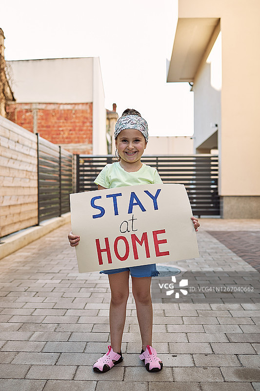 疫情期间举着居家标语牌的微笑儿童图片素材