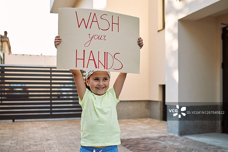 疫情期间快乐的女孩拿着洗手提示牌图片素材