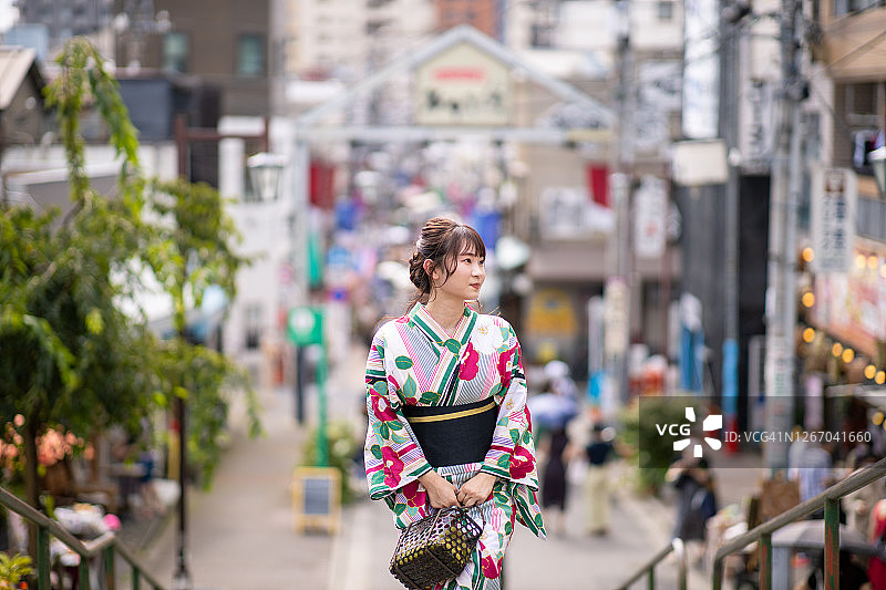 身穿浴衣的年轻女子在商业街上拾阶而上图片素材