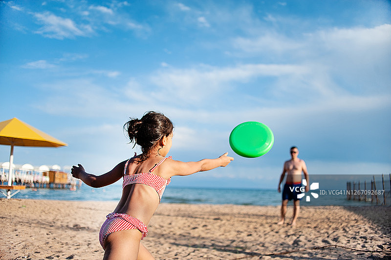 家人在海滩玩飞盘，女儿和父亲一起玩耍图片素材