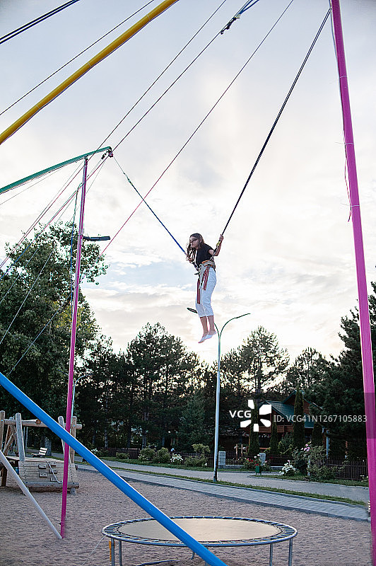 女孩在蹦极跳床上跳跃图片素材