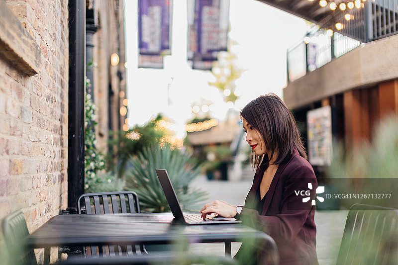 在工业风格的户外咖啡馆工作的年轻有为的自由职业女性图片素材