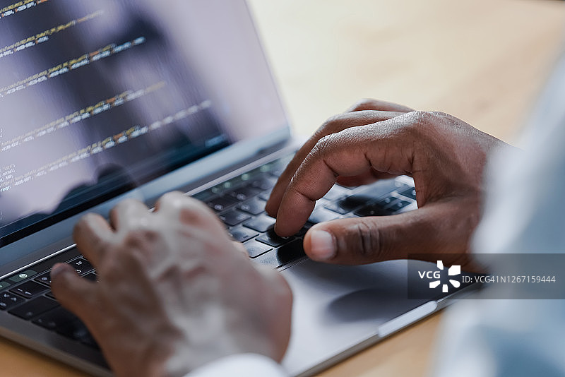 男子穿着衬衫在笔记本电脑上输入计算机程序文本图片素材