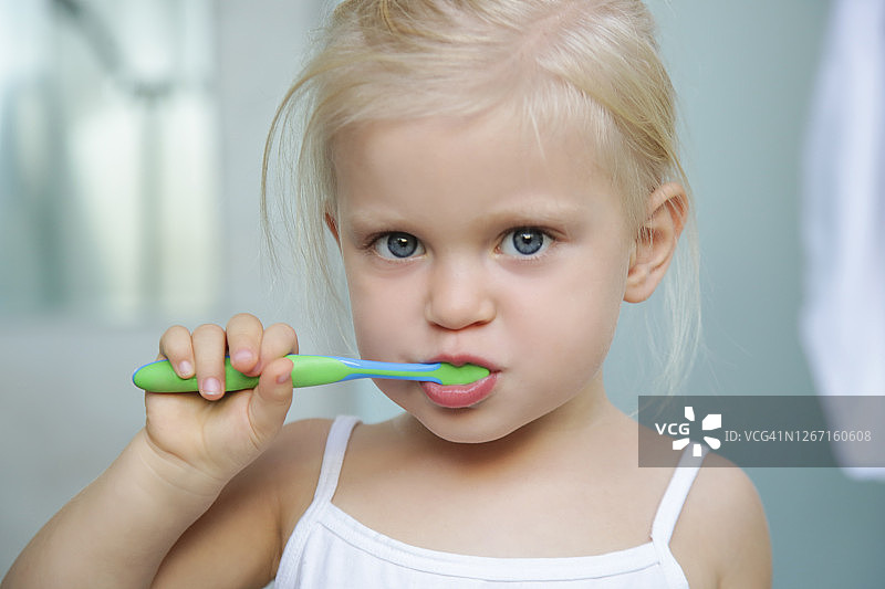 可爱的3岁女孩在浴室里刷牙图片素材