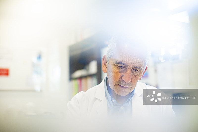 资深医生在医院的办公桌前工作图片素材