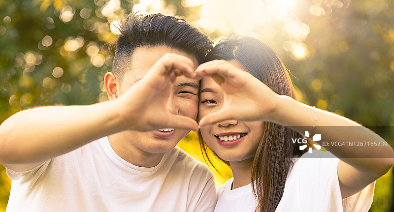 用手指比心的快乐的亚洲男孩和女孩图片素材