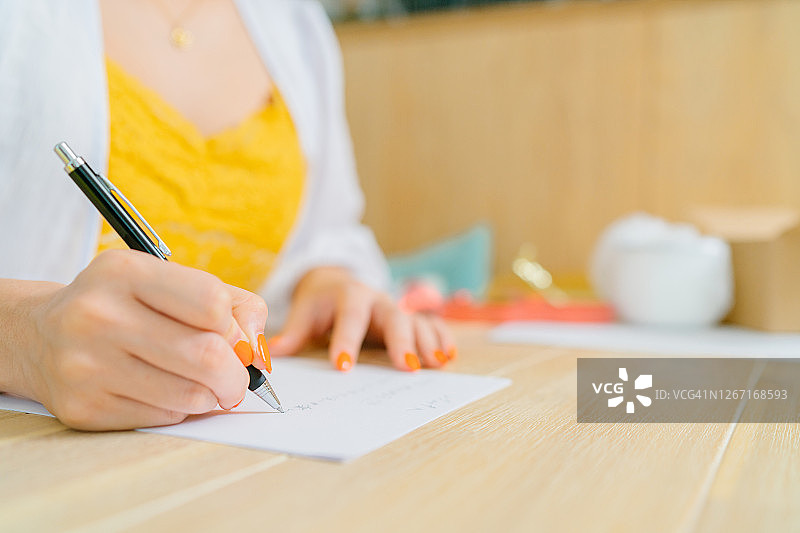 年轻女人在客厅里写信放入礼品盒中的手的特写照片图片素材