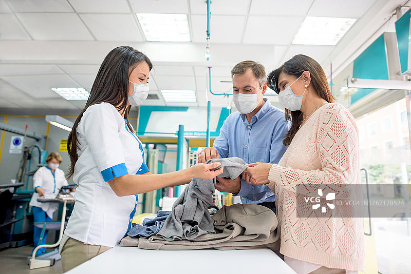 情侣戴着口罩去干洗店送洗衣物图片素材