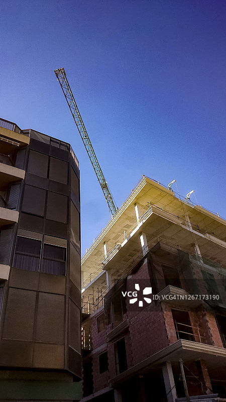 两栋建筑物上方的起重机，其中一栋在建图片素材