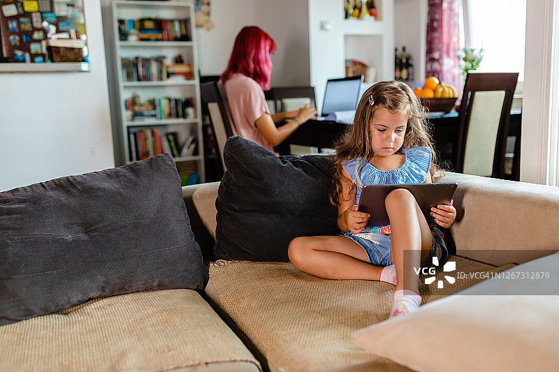 疫情期间，孤独的小女孩在家看平板电脑图片素材