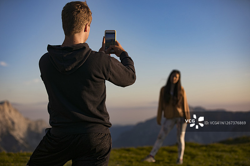 年轻男子在山中用手机拍摄年轻女子图片素材