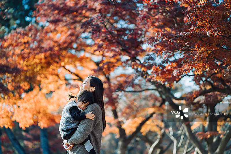 慈爱的亚洲母亲怀抱女儿在秋日公园图片素材