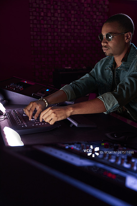 在音乐工作室的调音台上混合歌曲的非洲裔音乐制作人图片素材