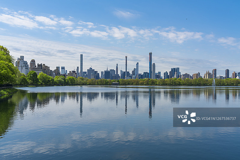 纽约中央公园西住宅区与中央公园水库的绿树倒影图片素材