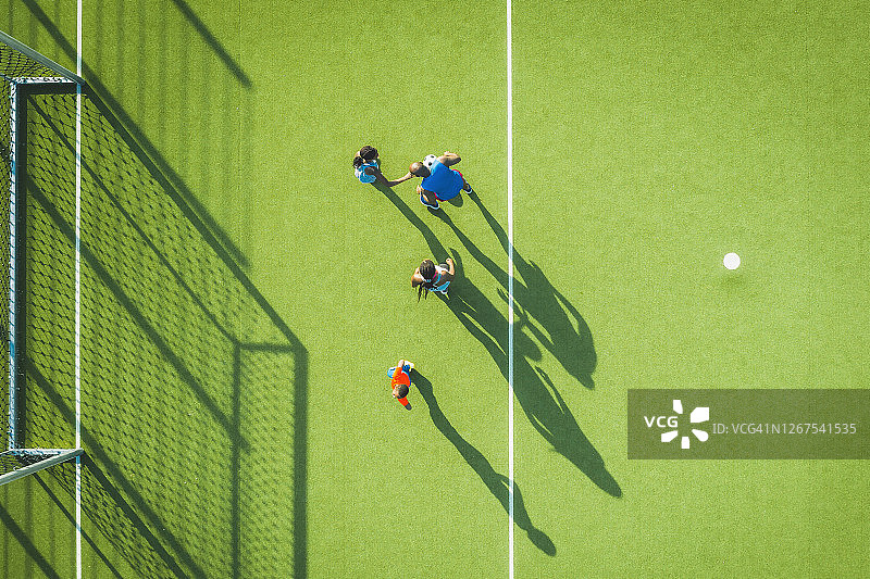 俯视视角：黑人家庭在绿色足球场上一起踢足球图片素材