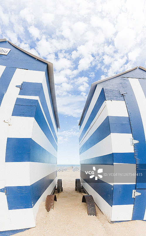 天空背景下并排的两个蓝白色海滩小屋图片素材