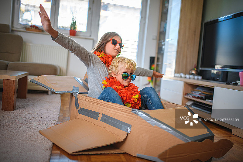 兄妹俩在室内玩纸板飞机图片素材