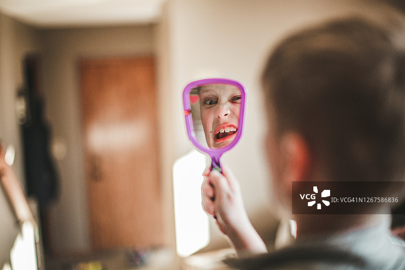 男孩拿着手镜做鬼脸图片素材
