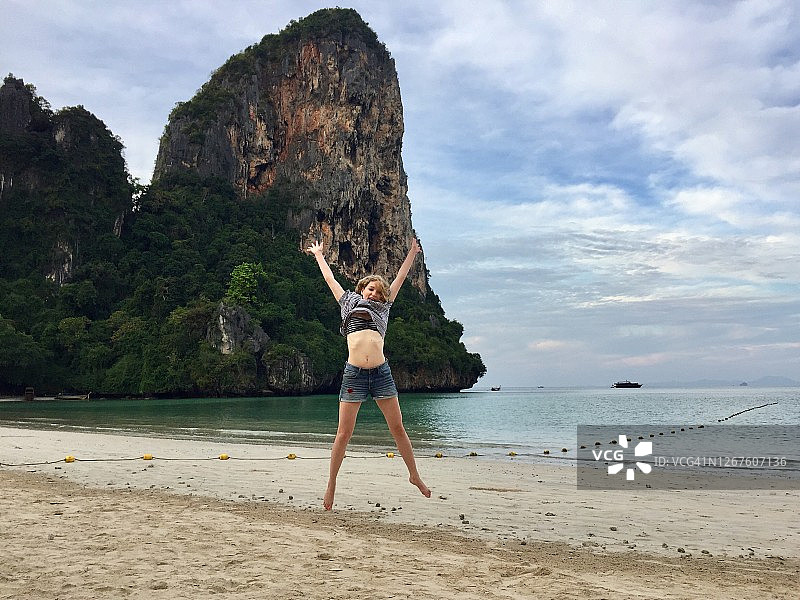 年轻女人在热带岛屿度假时高兴地跳跃图片素材