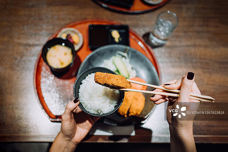 年轻女子享用日式套餐（味增汤、开胃菜和炸猪排）俯视图图片素材