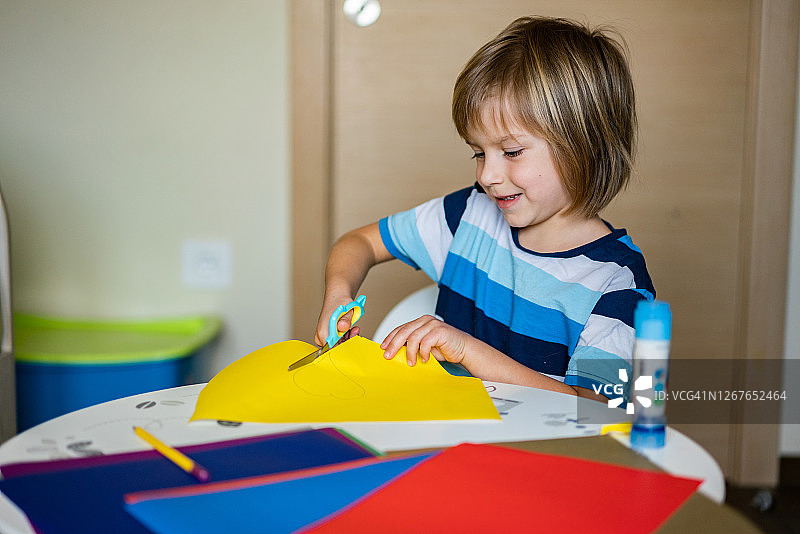用剪刀在纸上剪出形状的可爱男孩图片素材