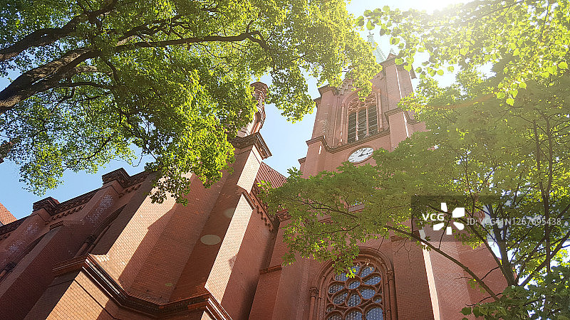 德国柏林沐浴在阳光下的红色砖砌哥特式教堂和钟楼图片素材