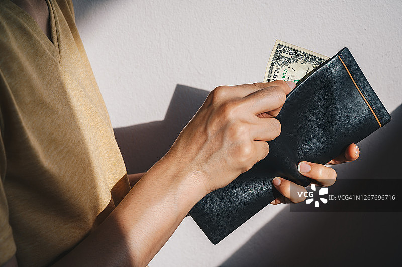 绝望的女人打开空钱包，发现只有一张美元钞票的特写图片素材