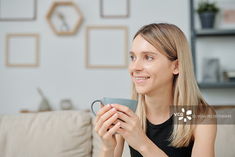 年轻漂亮的女人拿着咖啡杯在家享受休闲时光图片素材