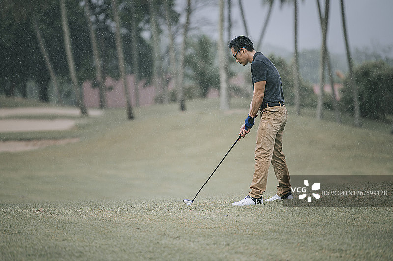 中国亚洲男高尔夫球手在马六甲雨中独自打高尔夫图片素材