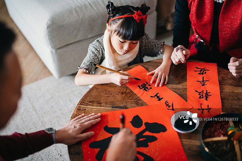 祖父母练习中国书法，书写新年挥春（吉祥话），并在家中教孙女写对联图片素材