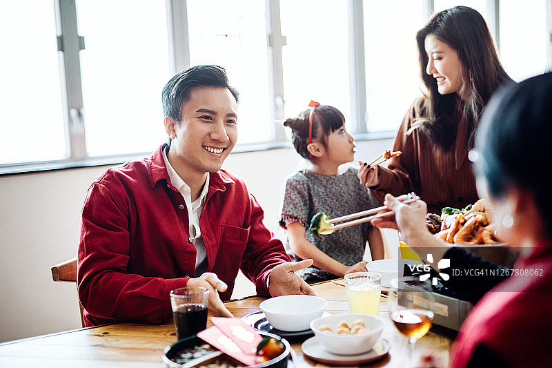 喜庆的亚洲家庭欢度中国新年，团圆饭享用美味的传统盆菜图片素材
