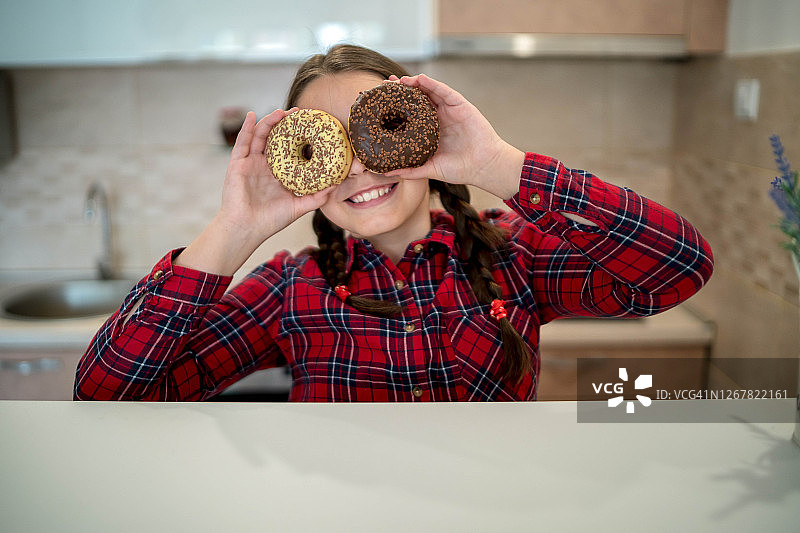 微笑的少女用甜甜圈遮住眼睛图片素材