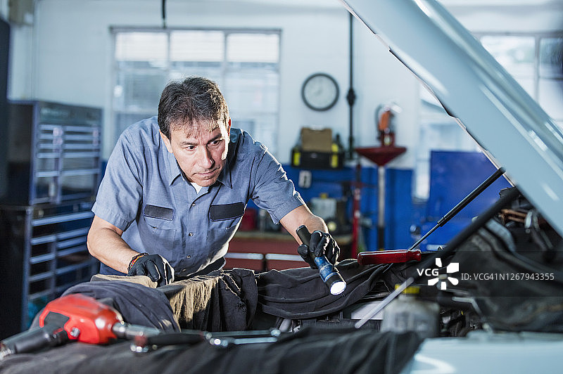在汽车修理店工作的年长的西班牙裔男人图片素材