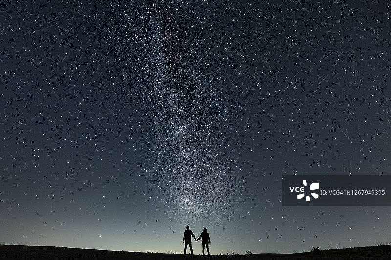 在银河系下牵手的夫妇图片素材