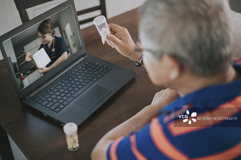 远程医疗：亚裔中国老年男性在家与医生进行视频会议图片素材
