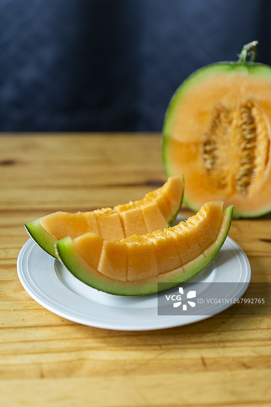 在木桌上切日本甜瓜，带文案空间图片素材