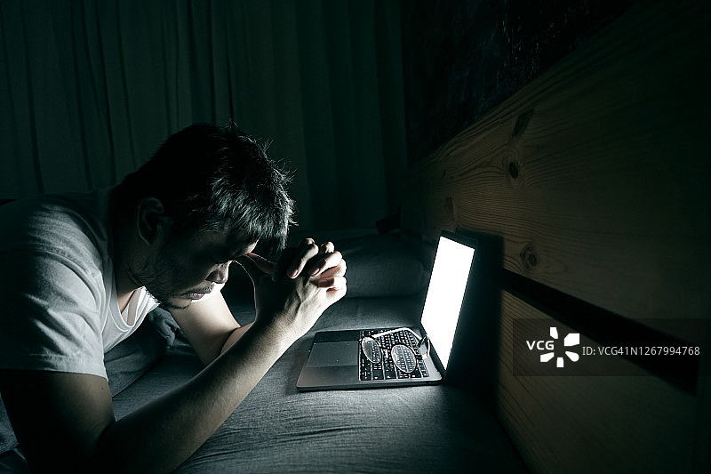 亚洲年轻人在床上使用笔记本电脑，感到疲惫不堪图片素材