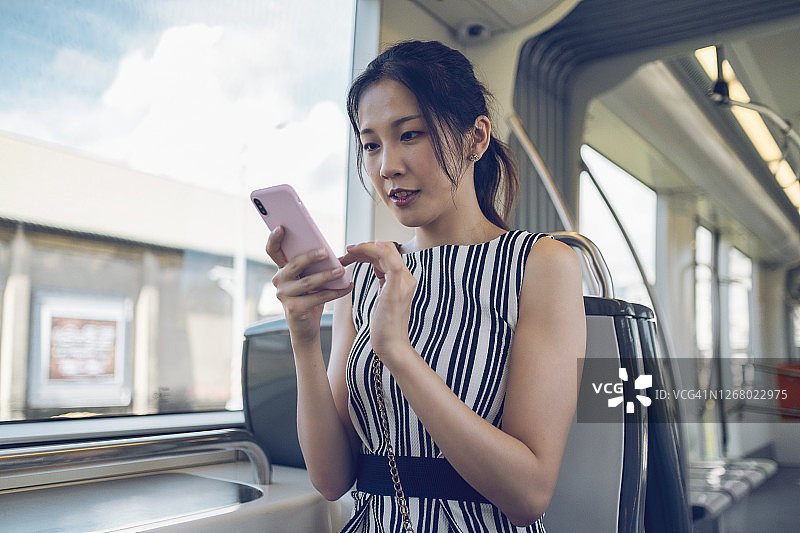 年轻女子在城市地铁通勤时使用手机图片素材