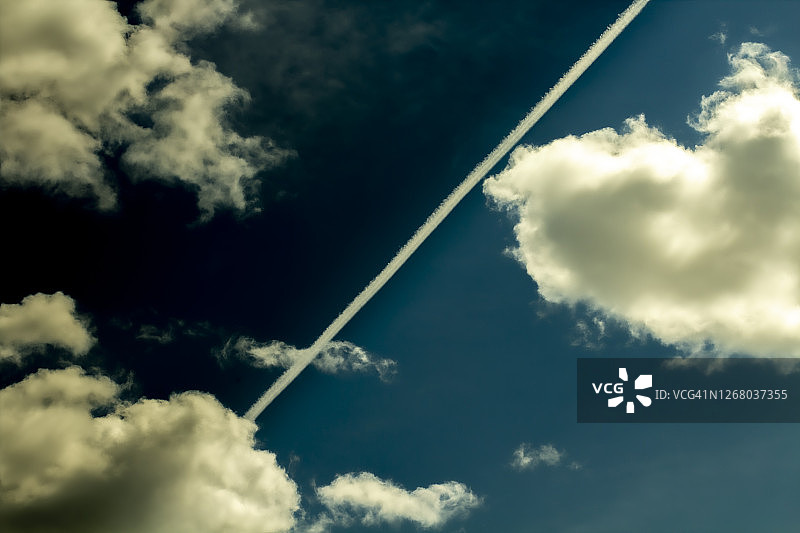 飞机尾迹划过天空，深蓝色调渲染环境问题与异常天气概念，天气预报文案背景图片素材