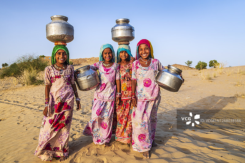 印度年轻女孩从井里取水，沙漠村庄图片素材