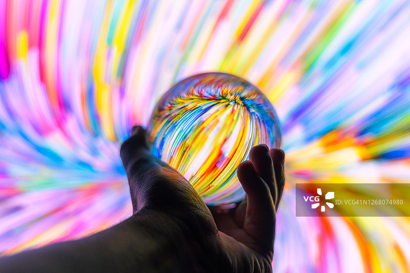 夜晚透过彩色背景手持水晶球图片素材