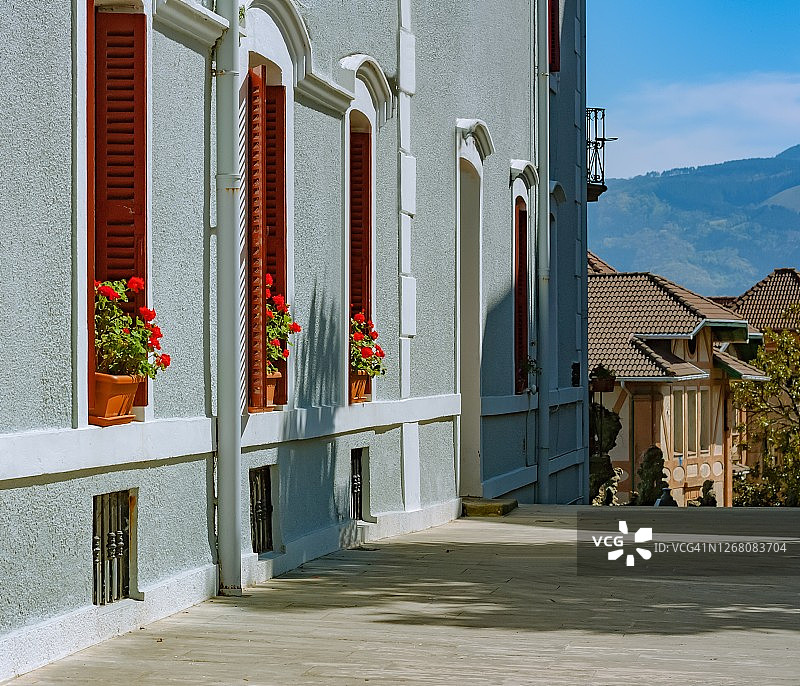 西班牙翁达里比亚的街道，一栋带有红色窗户的典型房屋，背景是山图片素材