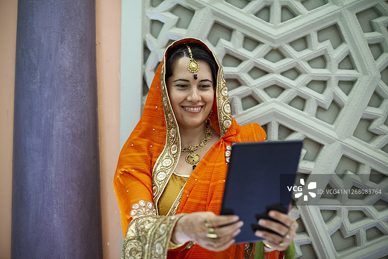 微笑的印度女孩使用她的平板电脑图片素材