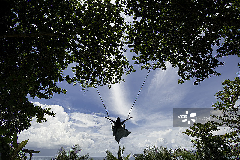 以美丽天空为背景的巨型秋千上的女孩图片素材
