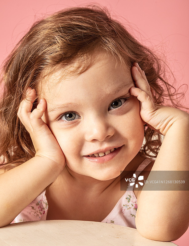 粉色背景前的可爱小女孩特写图片素材