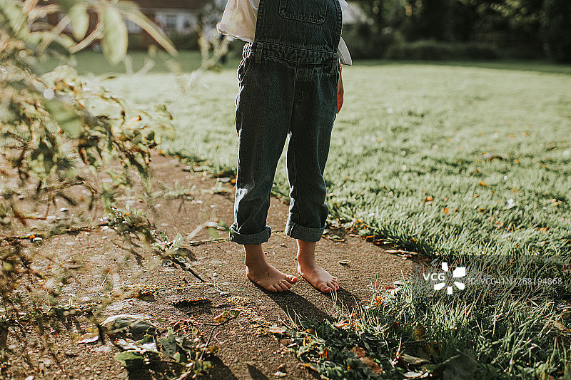 赤脚儿童站在低矮阳光下的铺路石上图片素材