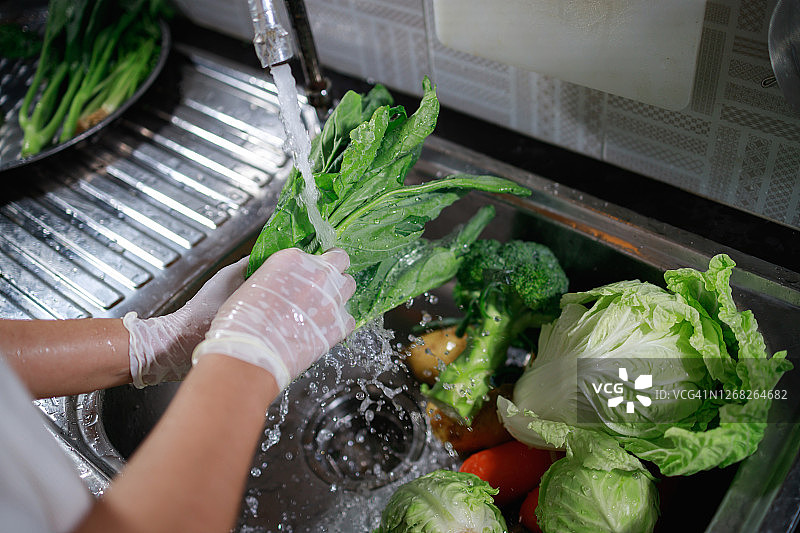 女人戴手套用清水清洗羽衣甘蓝图片素材