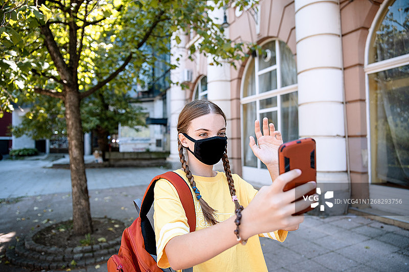 戴着黑色布口罩用手机聊天的少女图片素材