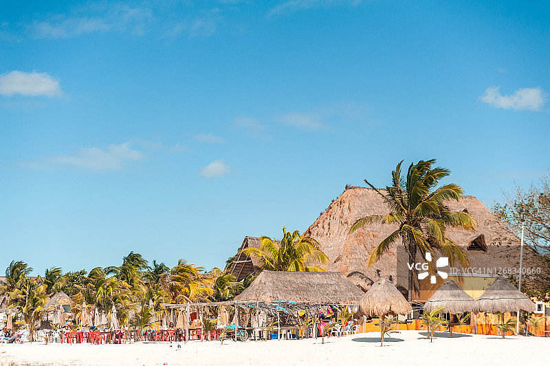 塞莱斯顿海滩上的售货亭和棚屋，棕榈树、椅子、桌子，晴朗的蓝天图片素材