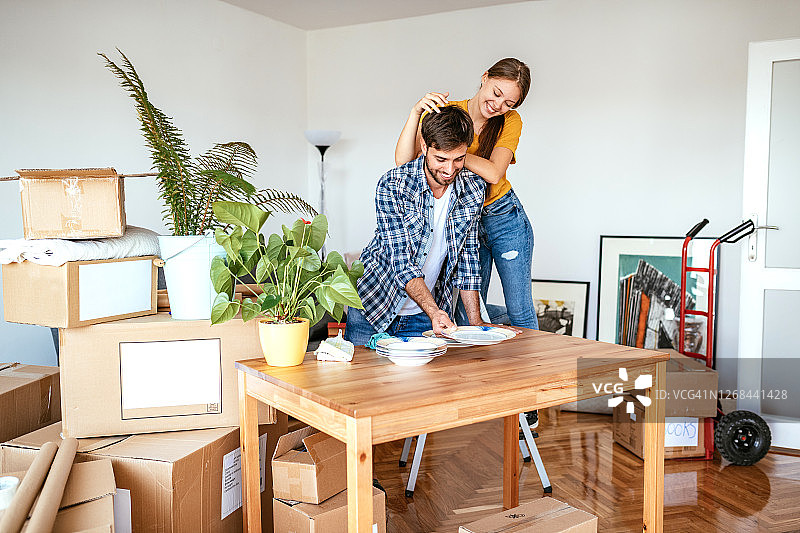 情侣搬进新公寓，打开盒子取出餐具、书籍和衣服图片素材